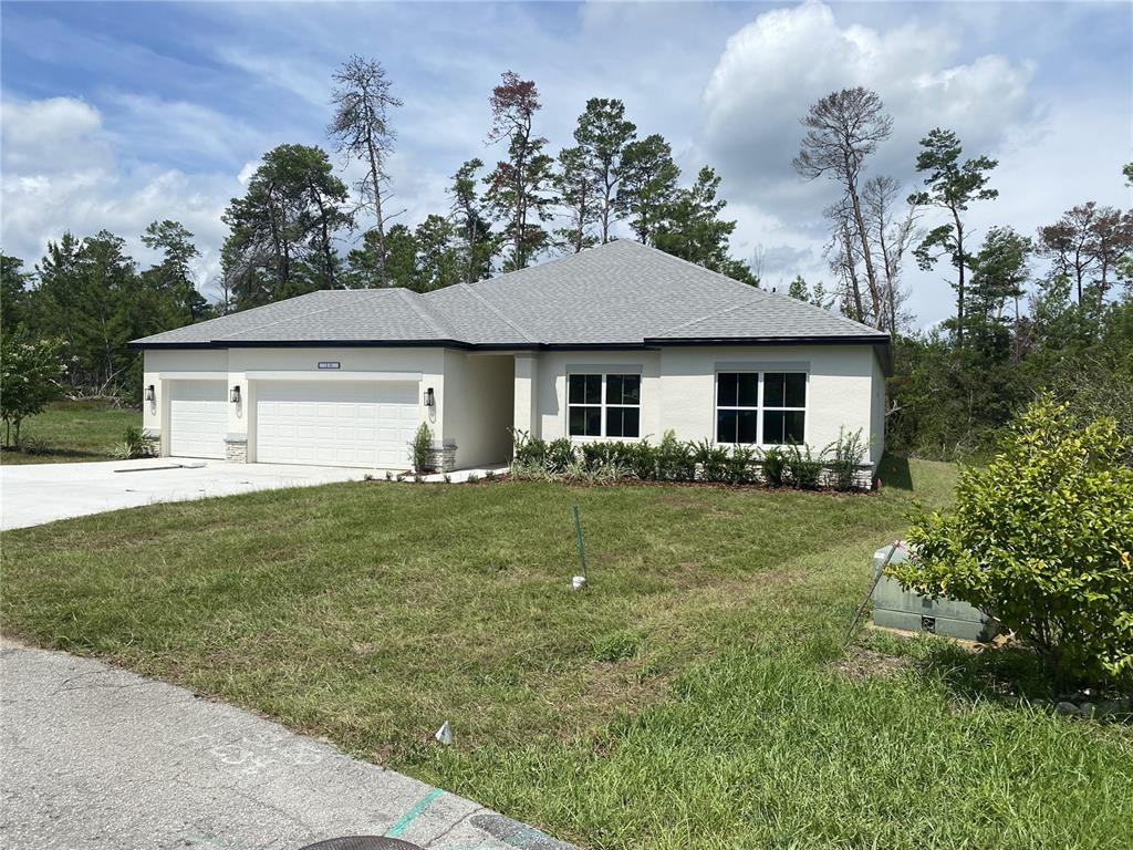 A single-story house with a white stucco exterior, a two-car garage, and a gray roof — 4 BELLIS COURT, HOMOSASSA, FL