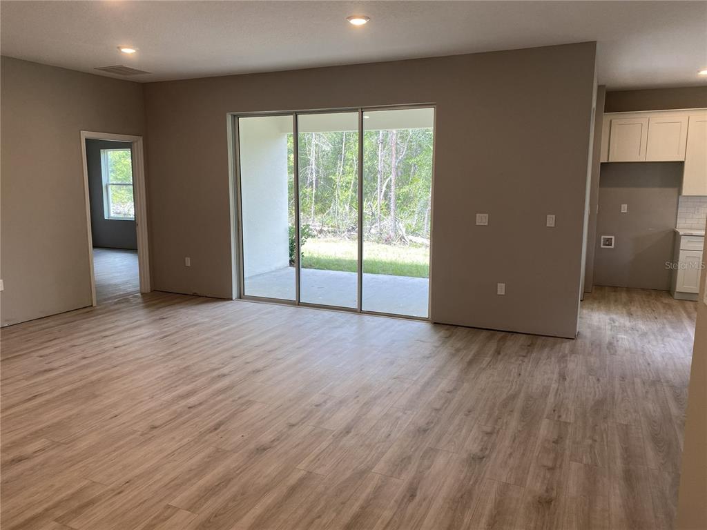 An open-concept living area features light wood-look flooring, recessed lighting, and sliding glass patio doors — 4 BELLIS COURT, HOMOSASSA, FL