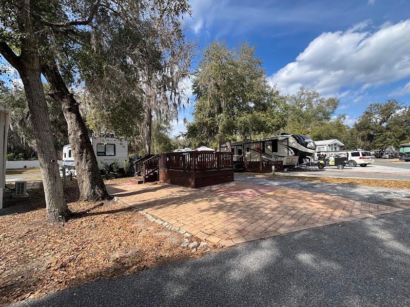 A paved patio area sits in front of a wooden deck and several parked RVs — 25146 NE 140TH LOOP UNIT 71, SALT SPRINGS, FL