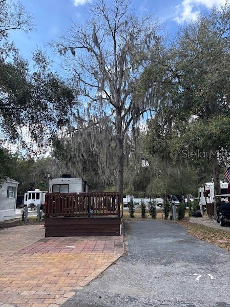 A paved driveway and brick patio lead to a wooden deck in front of an RV — 25146 NE 140TH LOOP UNIT 71, SALT SPRINGS, FL
