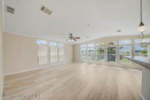 A bright, open-concept living area features light wood-look flooring and large windows — 9292 DENMARSH DRIVE, BROOKSVILLE, FL