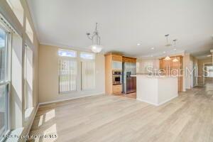 A bright kitchen features light wood flooring, wooden cabinets, and a central island — 9292 DENMARSH DRIVE, BROOKSVILLE, FL