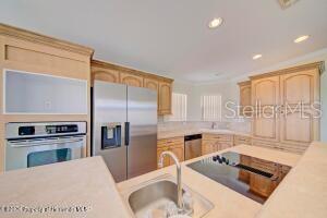 A kitchen features light wood cabinets, stainless steel appliances, and a central island with a sink — 9292 DENMARSH DRIVE, BROOKSVILLE, FL