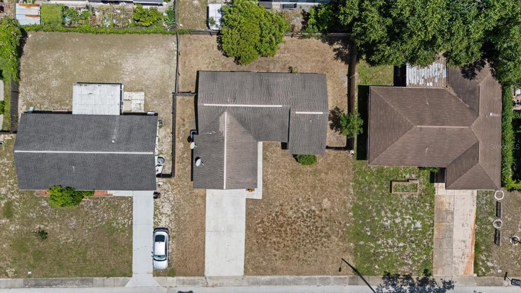 An aerial view shows three residential houses with driveways and yards along a street — 5102 MEADOWLARK LANE, NEW PORT RICHEY, FL
