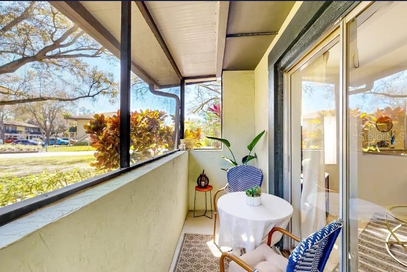 A screened-in balcony features a small bistro table with two chairs and a potted plant — 2900 LICHEN LANE UNIT B, CLEARWATER, FL