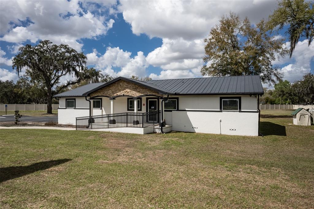 A single-story building with a white stucco exterior, dark metal roof, and wheelchair ramp — 7265 SW HIGHWAY 200, OCALA, FL
