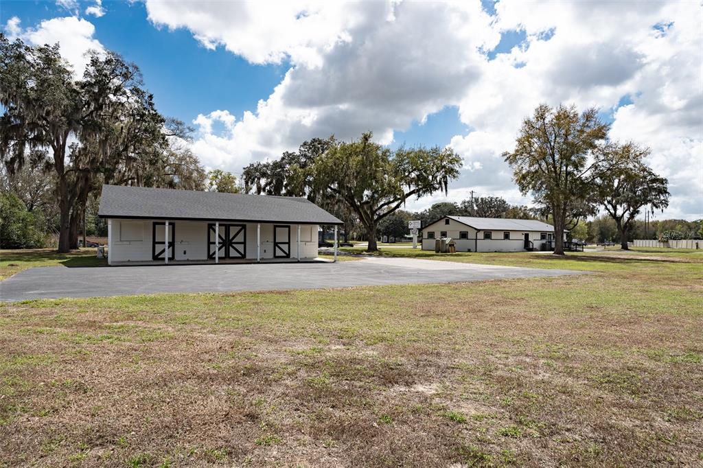 Two white buildings with dark roofs stand on a large, grassy lot with trees — 7265 SW HIGHWAY 200, OCALA, FL