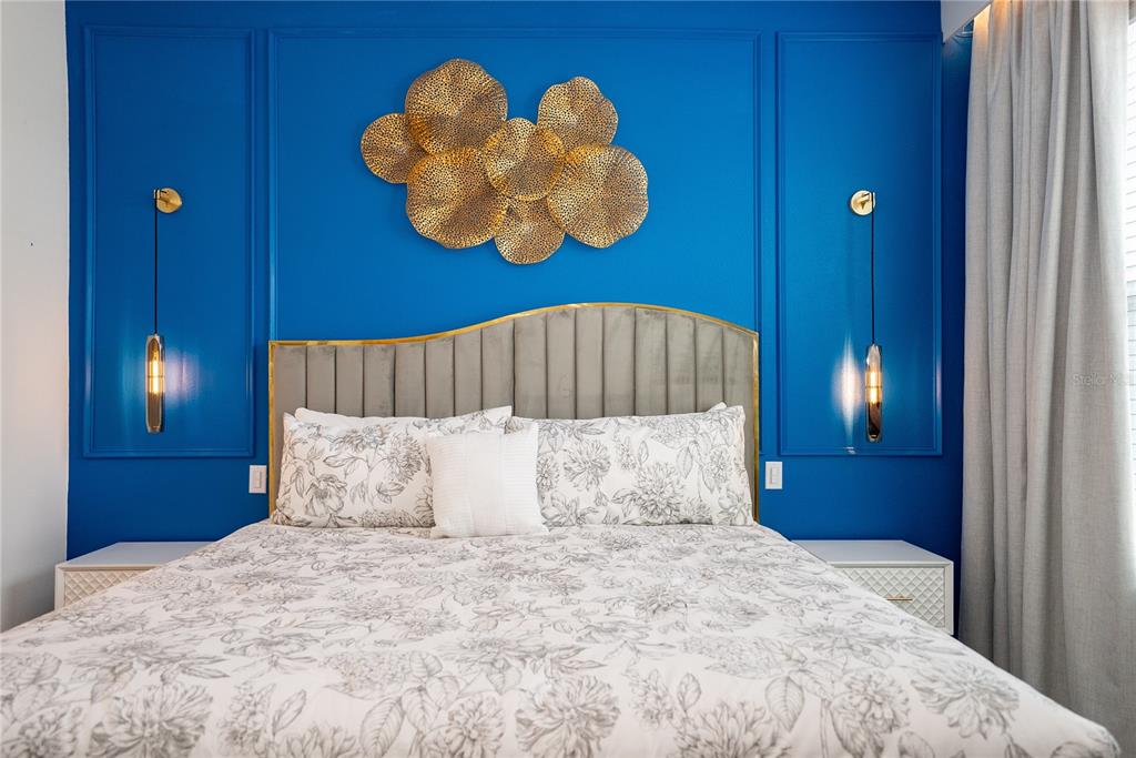 A bedroom features a blue accent wall with gold wall art and a gray headboard — 2379 DISTANT SUN TRAIL, KISSIMMEE, FL