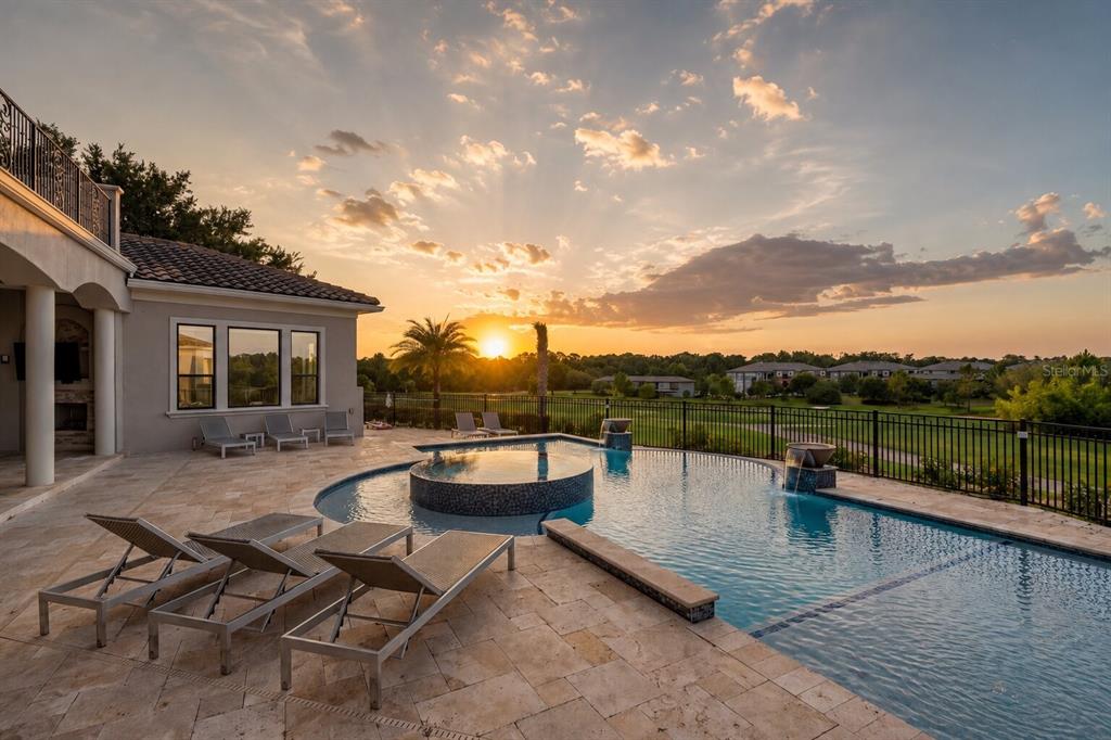 A backyard patio features a swimming pool with a spa and lounge chairs at sunset — 7829 PALMILLA COURT, KISSIMMEE, FL