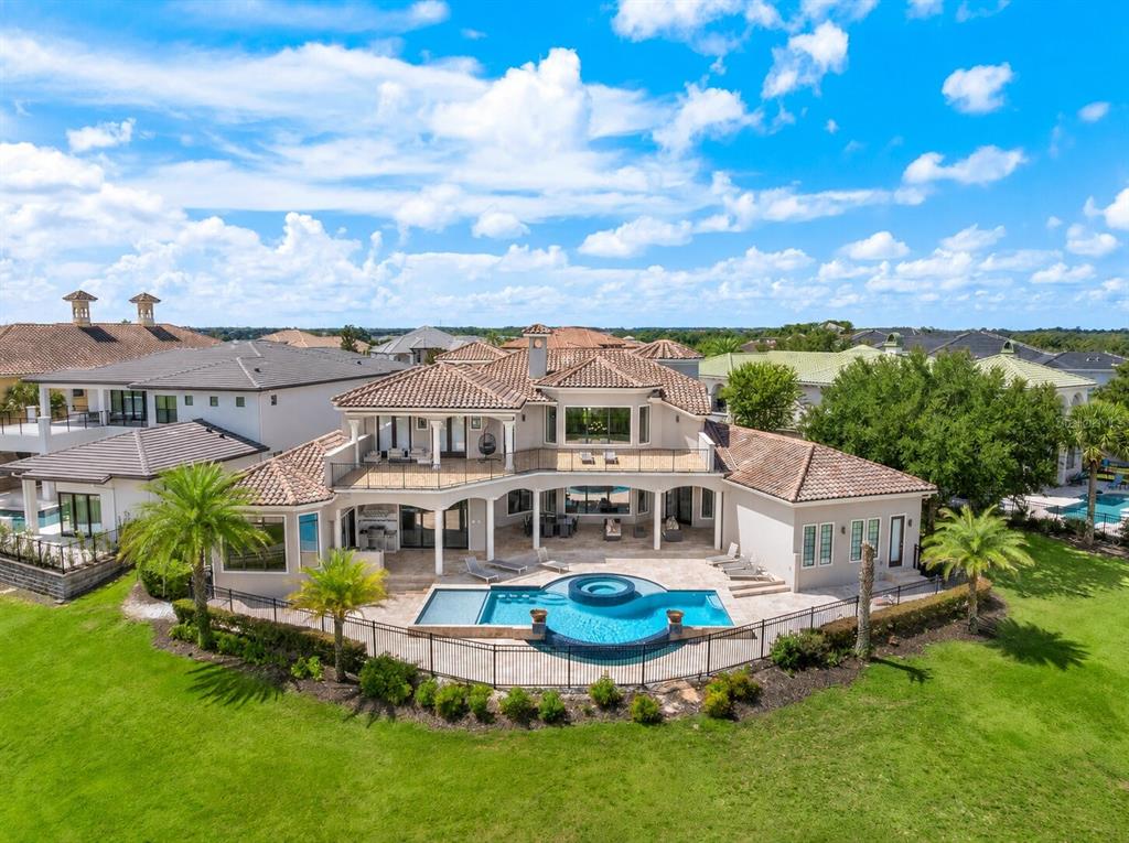 An aerial view of a two-story house with a tiled roof, pool, and fenced backyard — 7829 PALMILLA COURT, KISSIMMEE, FL