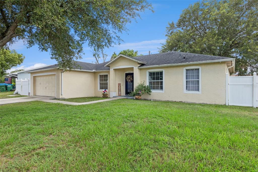 A single-story house with a beige stucco exterior, a garage, and a front lawn — 939 CLOVERLEAF BOULEVARD, DELTONA, FL