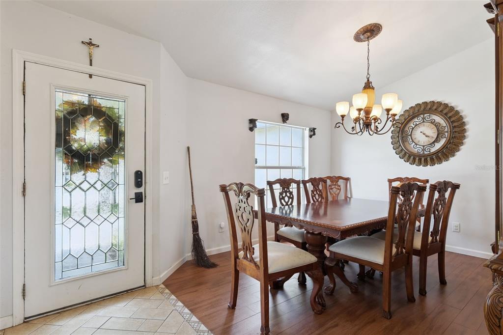 A dining room features a wooden table, six chairs, a chandelier, and a front door — 939 CLOVERLEAF BOULEVARD, DELTONA, FL
