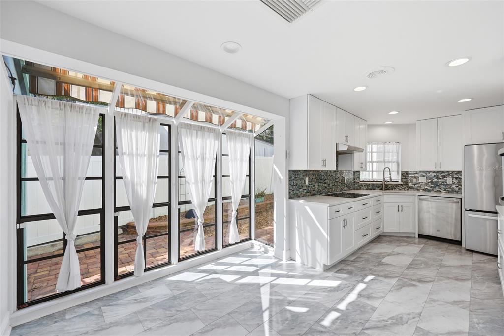 A bright kitchen features white cabinets, a mosaic tile backsplash, and a large windowed wall — 17 HIBISCUS COURT, EUSTIS, FL