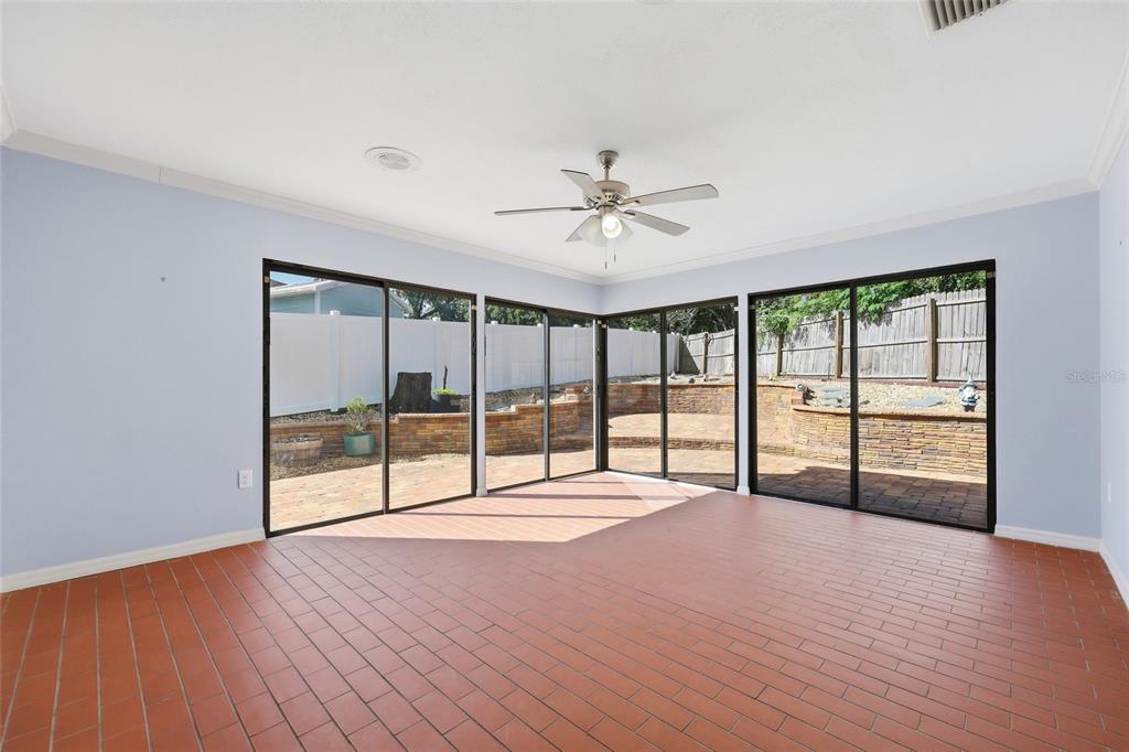 A sunroom with light blue walls, red tile flooring, a ceiling fan, and sliding glass doors — 17 HIBISCUS COURT, EUSTIS, FL