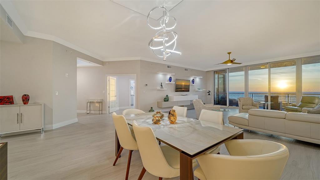 A modern dining and living area features a marble table, contemporary chandelier, and ocean views — 535 SANCTUARY DRIVE UNIT C807, LONGBOAT KEY, FL