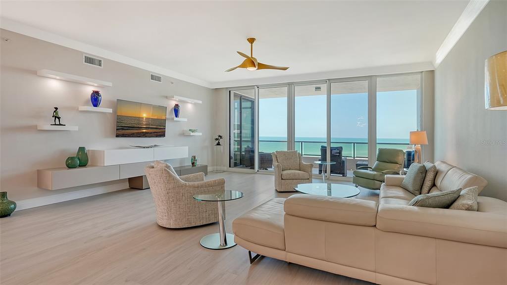 A modern living room features a large sectional sofa, swivel chairs, and floor-to-ceiling ocean views — 535 SANCTUARY DRIVE UNIT C807, LONGBOAT KEY, FL