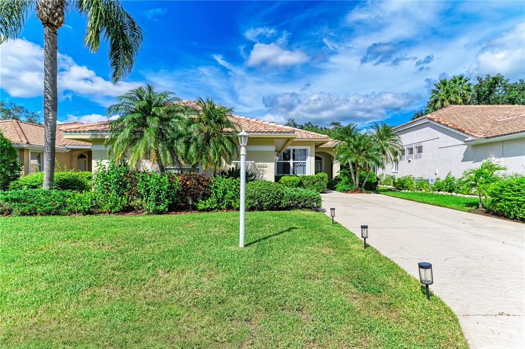 A single-story house with a tile roof, palm trees, and a concrete driveway — 6622 OAKBROOKE CIRCLE, BRADENTON, FL
