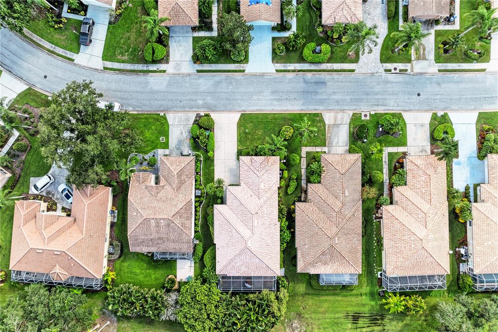 An aerial view shows several suburban houses with tiled roofs and driveways along a street — 6622 OAKBROOKE CIRCLE, BRADENTON, FL