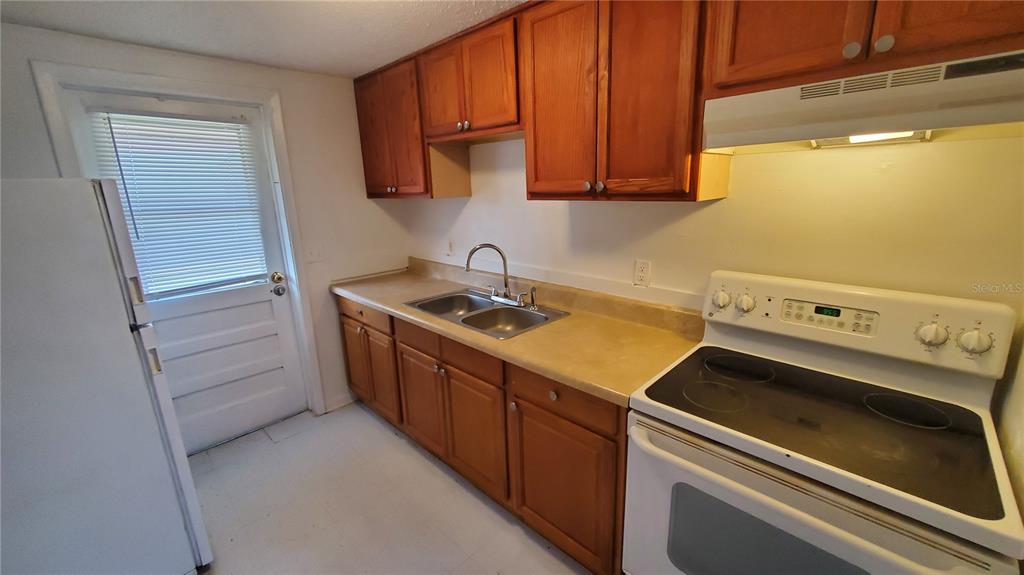 A kitchen features wood cabinets, a double-basin sink, a white stove, and a white refrigerator — 818 6TH STREET SE, FORT MEADE, FL