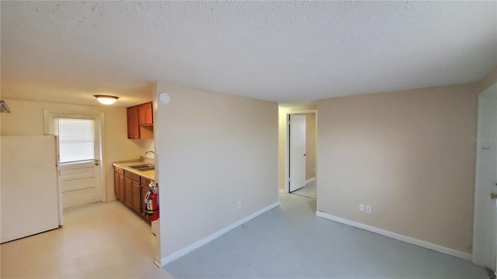 A kitchen with wood cabinets and a white refrigerator sits adjacent to an open room — 818 6TH STREET SE, FORT MEADE, FL