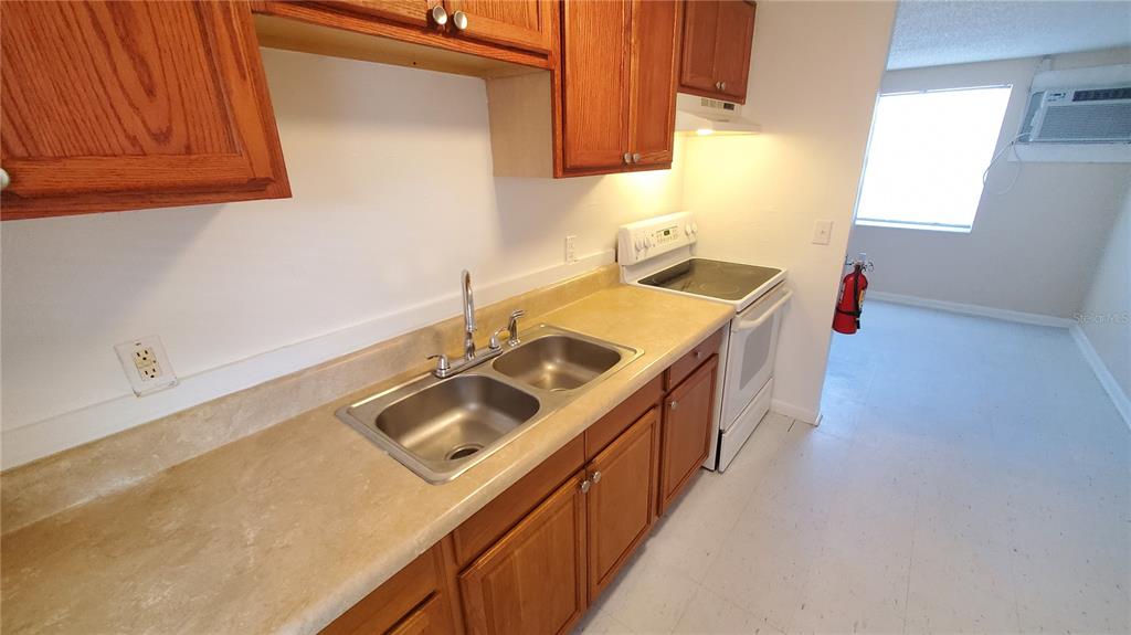A kitchen features wood cabinets, a double-basin sink, laminate countertops, and a white electric stove — 818 6TH STREET SE, FORT MEADE, FL