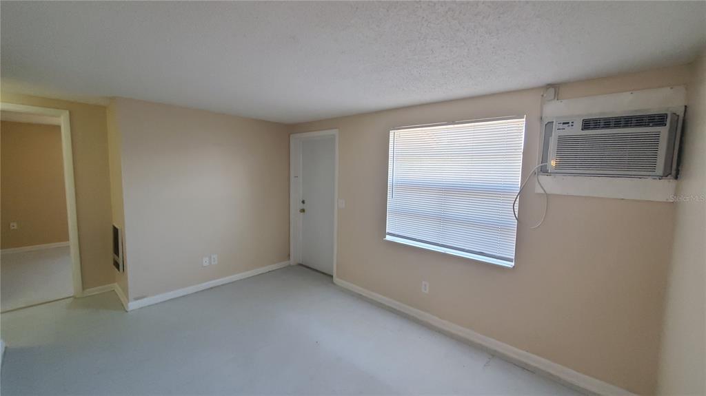 An empty room features beige walls, a window with blinds, and a wall-mounted air conditioner — 818 6TH STREET SE, FORT MEADE, FL