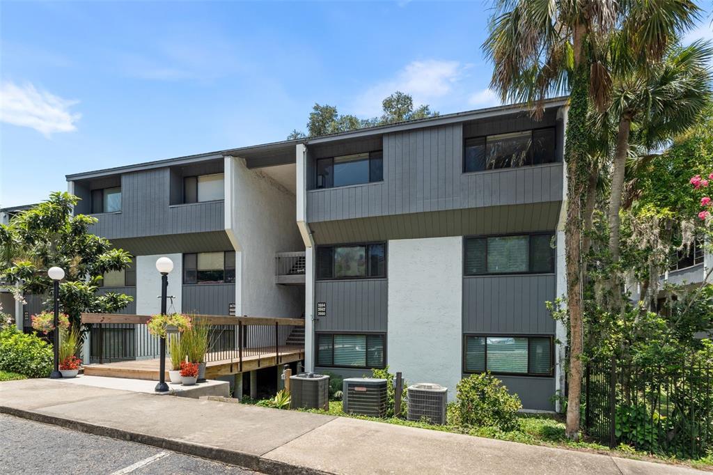 A multi-story apartment building features gray siding, white stucco walls, and an elevated wooden walkway — 2660 SW 14TH DRIVE, GAINESVILLE, FL
