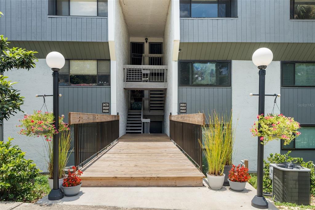 A wooden bridge leads to the entrance of a multi-story apartment building with gray siding — 2660 SW 14TH DRIVE, GAINESVILLE, FL