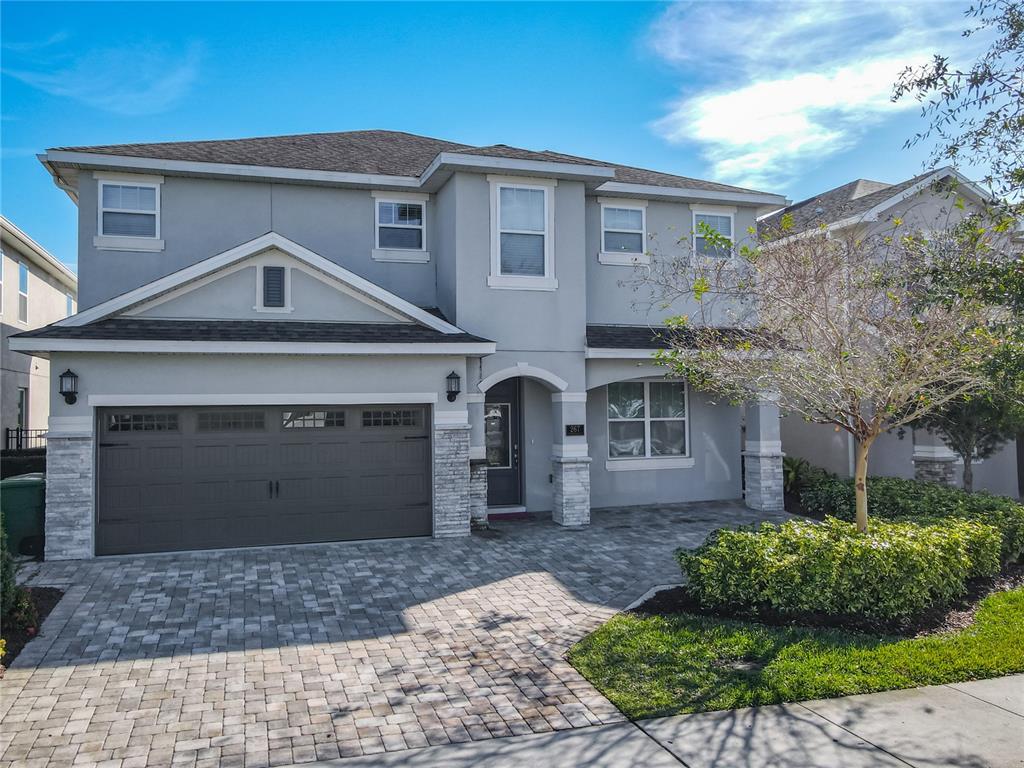 A two-story house with a gray stucco exterior, stone accents, and a paved driveway — 267 SOUTHFIELD STREET, KISSIMMEE, FL