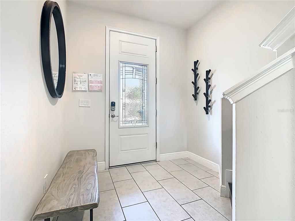An entryway features a white front door, a wooden bench, and two wall-mounted coat racks — 267 SOUTHFIELD STREET, KISSIMMEE, FL