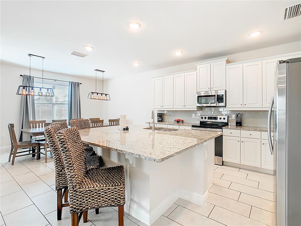 A kitchen features white cabinets, granite countertops, a large island, and an adjacent dining area — 267 SOUTHFIELD STREET, KISSIMMEE, FL
