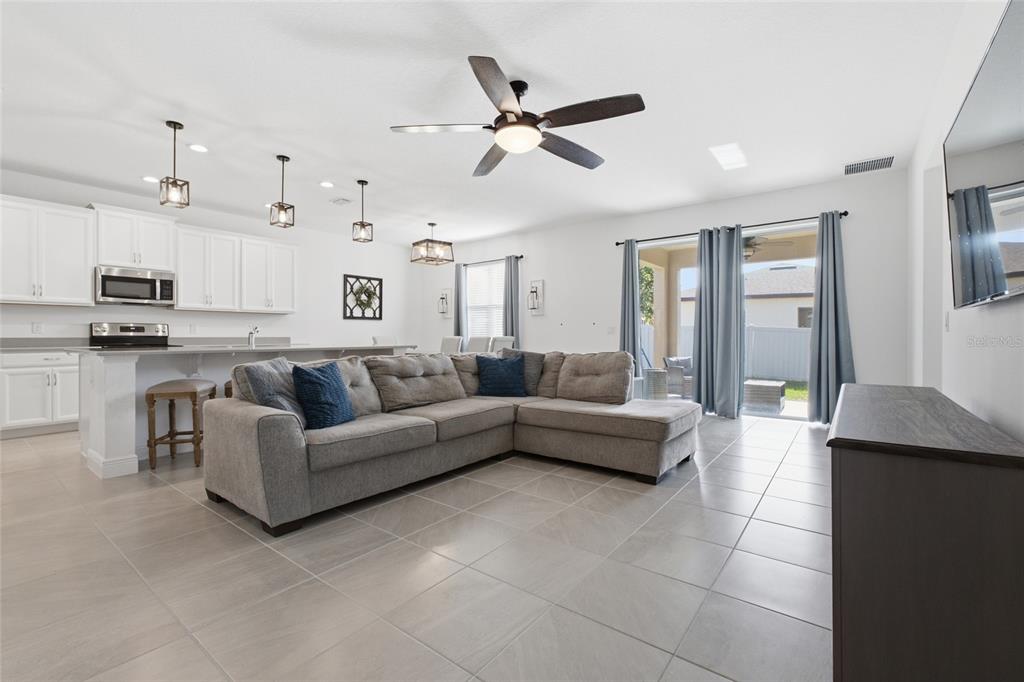 A living room with a gray sectional sofa, tile floors, and an open kitchen — 180 JENSEN DRIVE, GROVELAND, FL