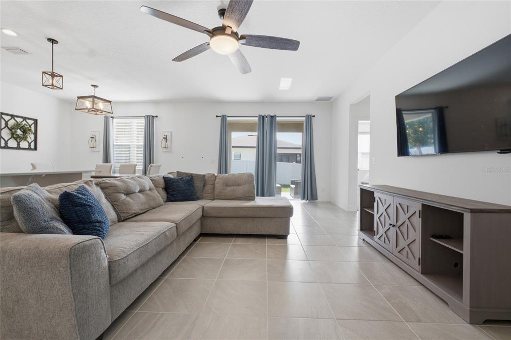 A living room features a gray sectional sofa, a television, and tile flooring — 180 JENSEN DRIVE, GROVELAND, FL