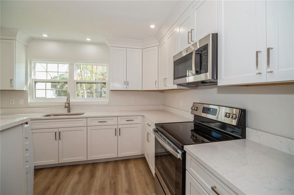A kitchen with white cabinets, stainless steel appliances, and light-colored countertops — 2018 MANOR DRIVE NE, PALM BAY, FL