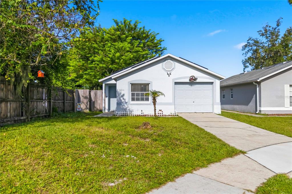 A single-story house with a light-colored stucco exterior, a front door, and a garage — 2200 ROSE BROOK COURT, ORLANDO, FL