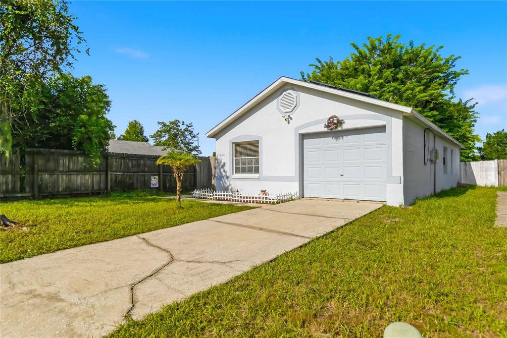 A covered concrete patio features a small metal table and two chairs against a block wall — 2200 ROSE BROOK COURT, ORLANDO, FL