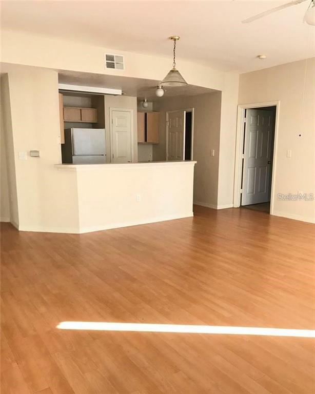 An open-concept living area features light wood-look flooring and a kitchen with a breakfast bar — 2000 ERVING CIRCLE UNIT 102, OCOEE, FL