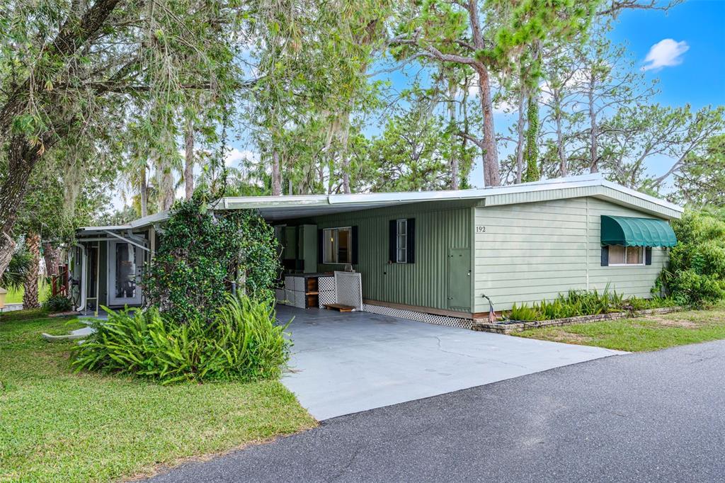 A light green mobile home with a carport and a small front yard — 192 PALM MEADOWS DRIVE, EUSTIS, FL