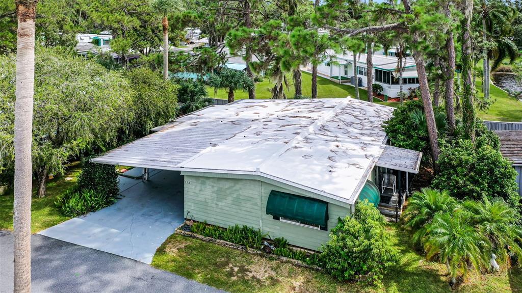 An elevated exterior view of a light green mobile home with a carport and white roof — 192 PALM MEADOWS DRIVE, EUSTIS, FL