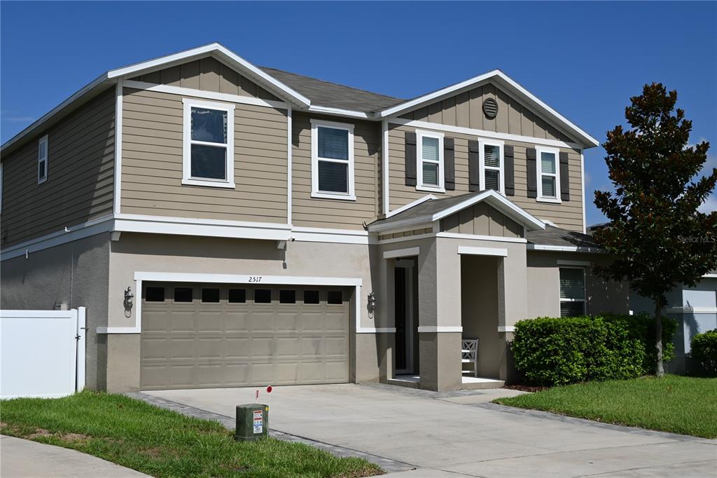 A two-story house with a tan stucco and siding exterior and a two-car garage — 2517 BISCOTTO CIRCLE, DAVENPORT, FL