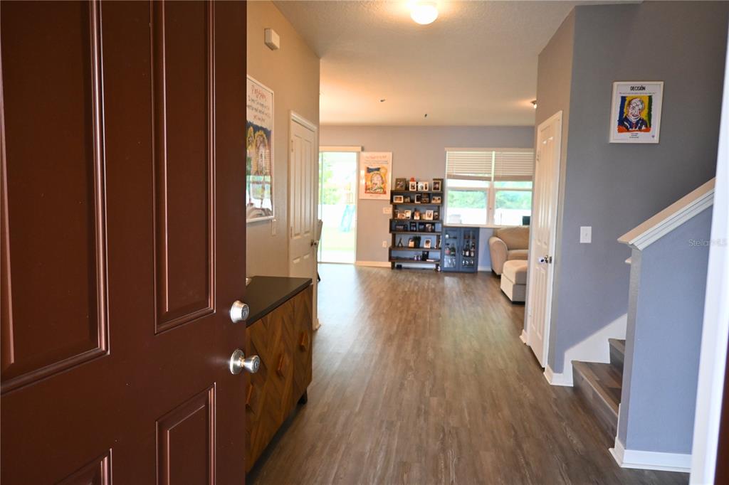 An entryway leads into an open living area with wood-look flooring and a staircase — 2517 BISCOTTO CIRCLE, DAVENPORT, FL