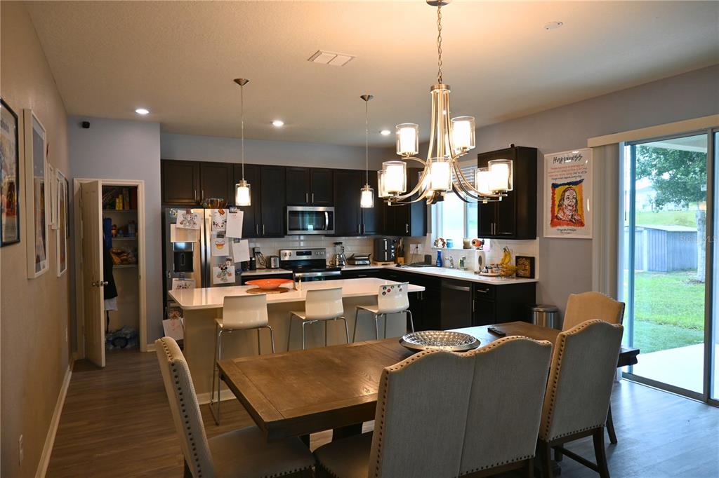 A kitchen with dark cabinets, a white island, and a dining area with a chandelier — 2517 BISCOTTO CIRCLE, DAVENPORT, FL