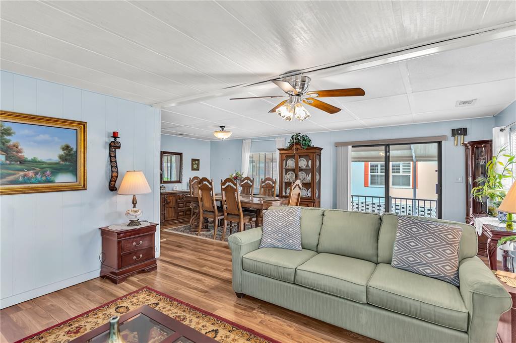 A living room with a green sofa flows into a dining area with wood flooring — 38546 STAFFORD DRIVE, ZEPHYRHILLS, FL