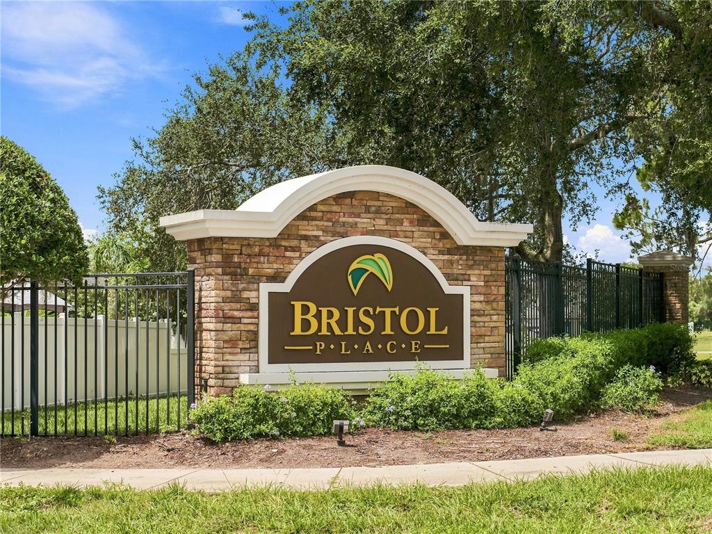 A stone monument sign for Bristol Place stands behind a black metal fence and landscaping — 14367 SALTBY PLACE, SPRING HILL, FL