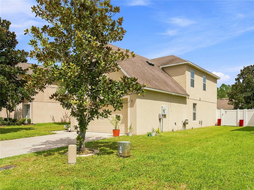 A two-story tan stucco house with a driveway, a tree, and a grassy yard — 14367 SALTBY PLACE, SPRING HILL, FL