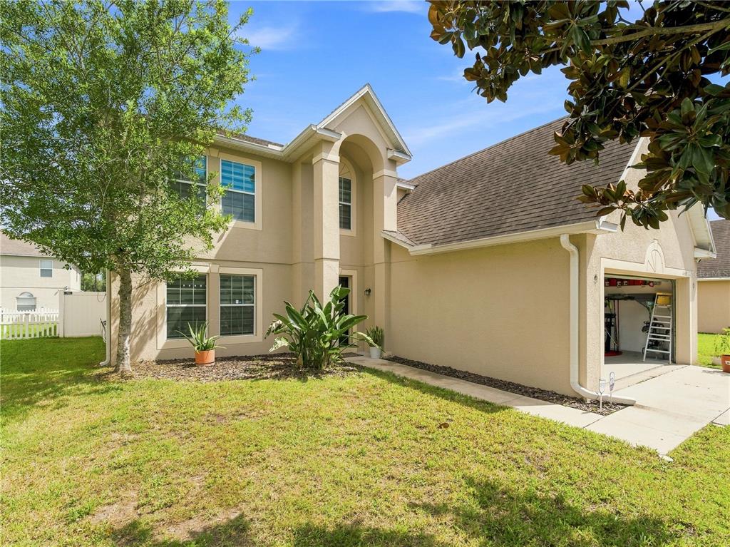 A two-story beige stucco house with a front-facing garage and a landscaped front yard — 14367 SALTBY PLACE, SPRING HILL, FL