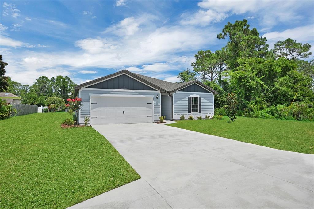 A single-story house with light blue siding, a two-car garage, and a concrete driveway — 153 PARKVIEW DRIVE, PALM COAST, FL