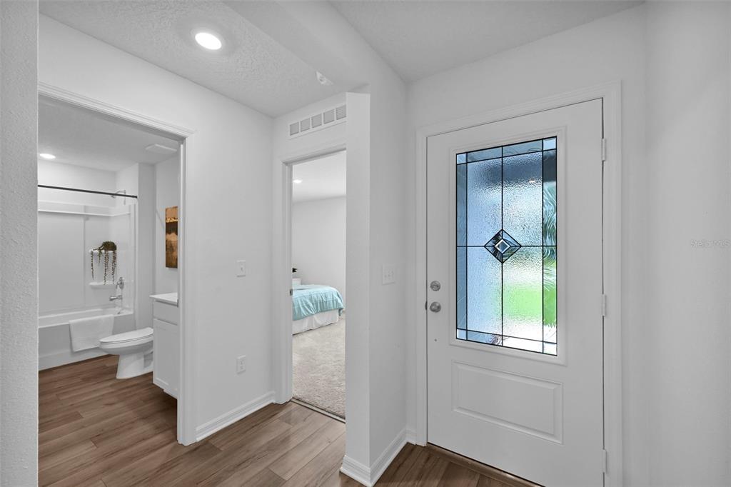 A white front door with a glass insert opens to a hallway with wood-look flooring — 153 PARKVIEW DRIVE, PALM COAST, FL
