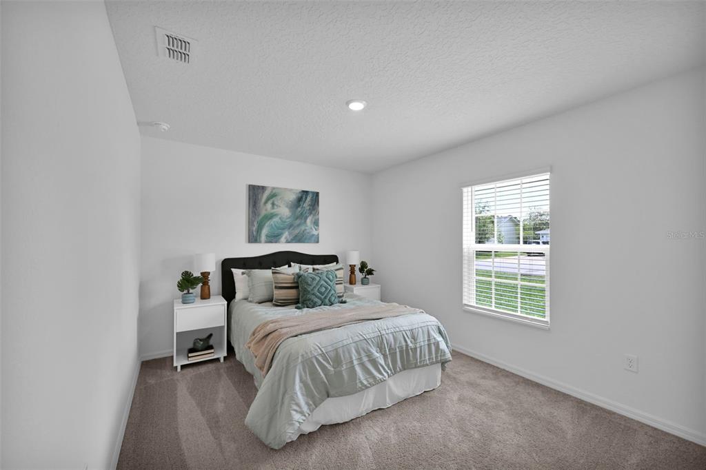 A bedroom with white walls, carpeted flooring, a bed with a dark headboard, and a window — 153 PARKVIEW DRIVE, PALM COAST, FL