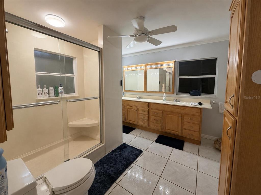 A bathroom features a glass-enclosed shower, a double vanity with wood cabinets, and tile flooring — 1205 LISA LANE, OKEECHOBEE, FL
